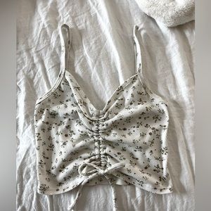 This is a small, cropped, white tank top with pink flowers from Tilly’s